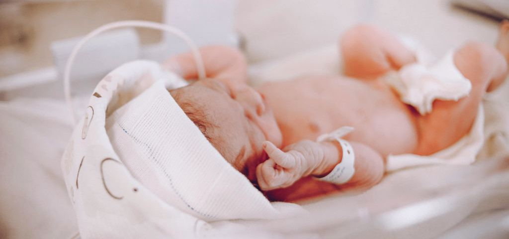 Neonato appena nato con cordone ombelicale, simbolo delle cellule staminali utili nella ricerca sulla cirrosi epatica infantile e nelle terapie innovative dopo intervento di Kasai